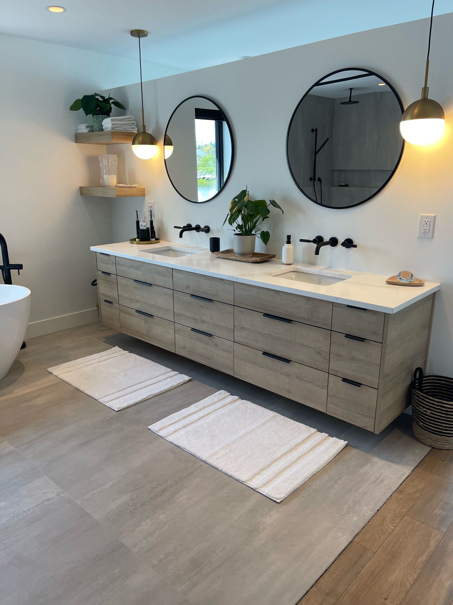 Double vanity with round mirrors, brass pendants and walk-in shower